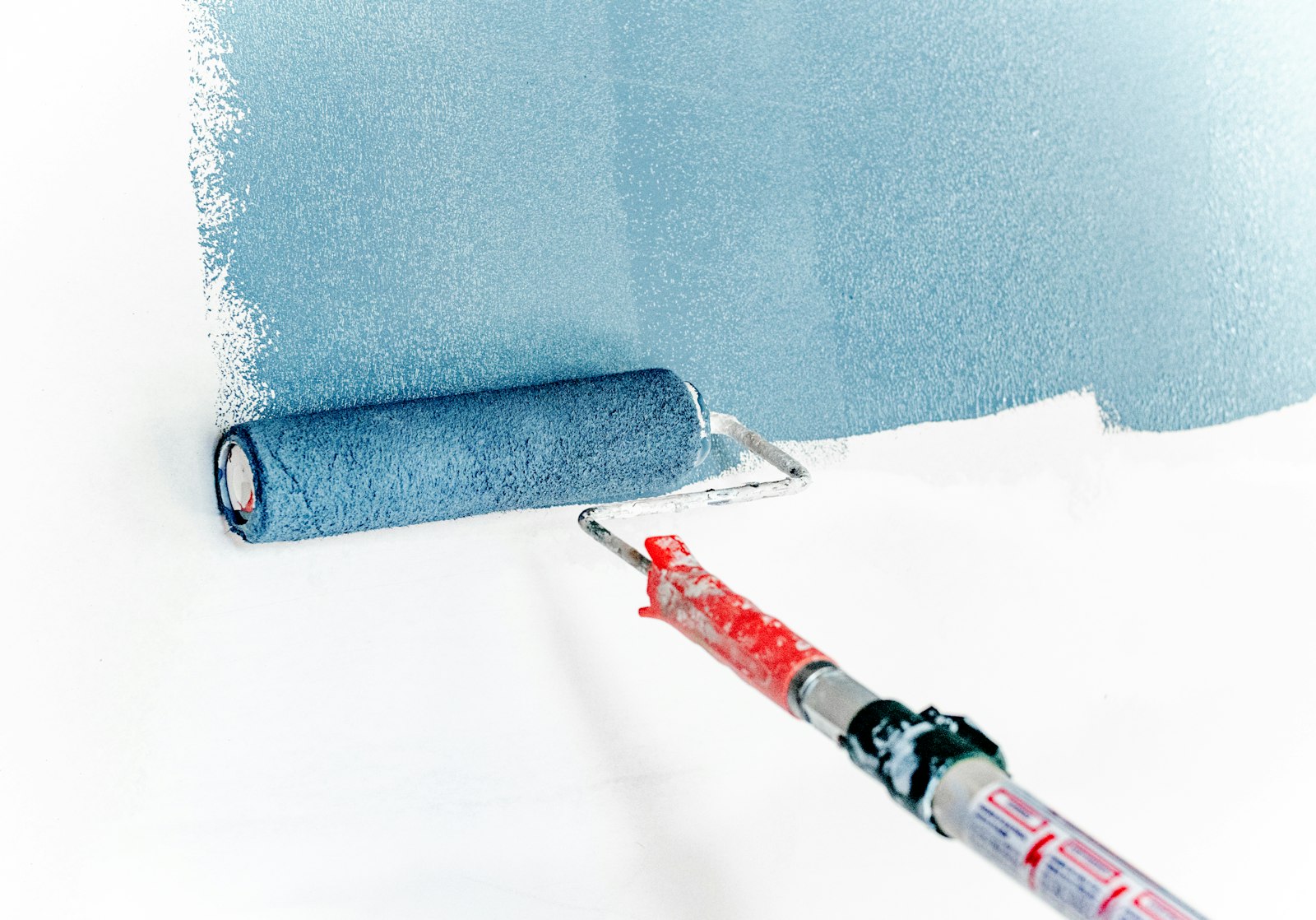 Painter rolling fresh white paint onto an interior wall